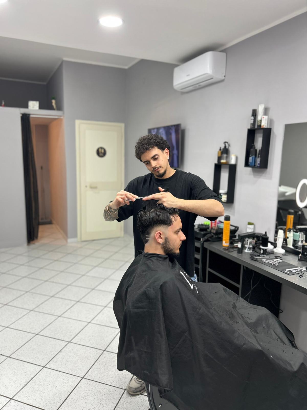 Luigi Cugno mentre taglia i capelli a un cliente nel salone LC Barber Professional